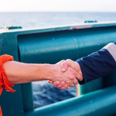 marine contractor businessman handshaking with worker on the ship. Handshake of two boilersuits with different color. Business shipping background